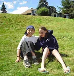 girlboy2 – Long Lake Camp For The Arts Two campers smiling while sitting on the grass.
