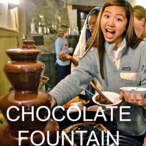 Campers dipping snacks in a chocolate fountain.