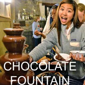 Campers dipping snacks in a chocolate fountain.
