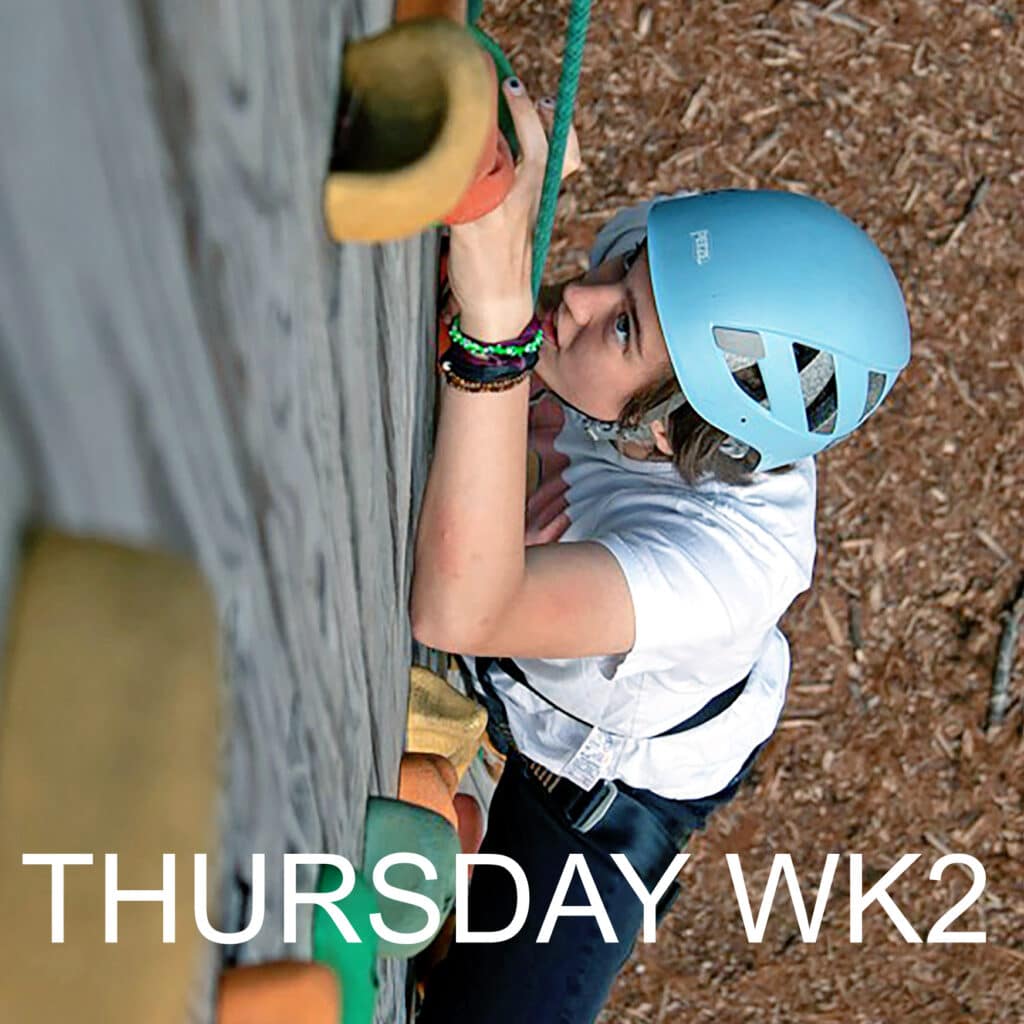 Climber scaling an outdoor rock wall during week two activities.