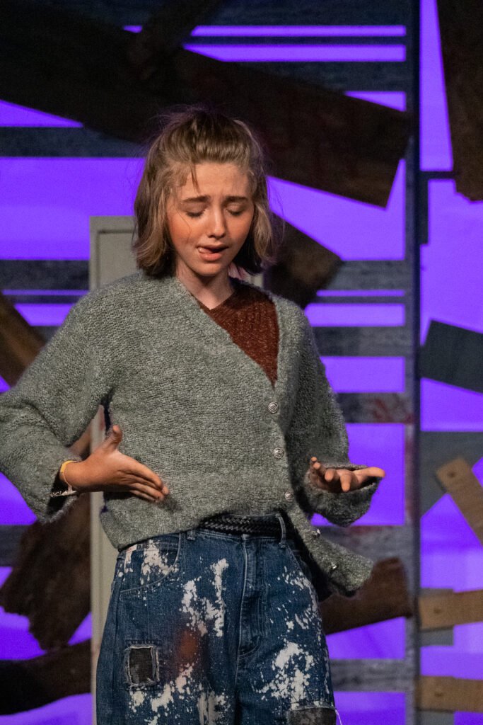 Youth actors performing a dramatic scene onstage at a summer theater camp.