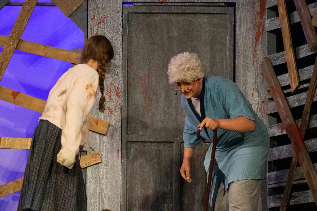 Campers acting in an intense zombie-themed stage production with dramatic set pieces.