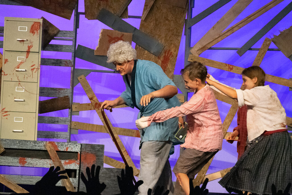 Youth actors performing a dramatic scene onstage at a summer theater camp.