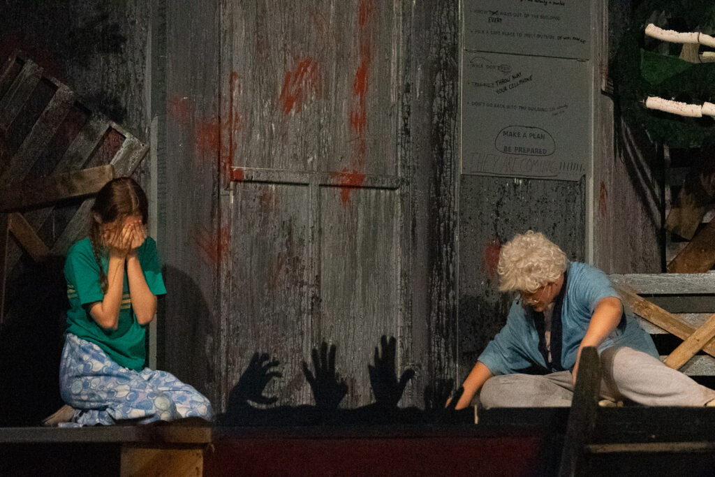 Campers performing a scene onstage with a rotary phone prop during a theater production.