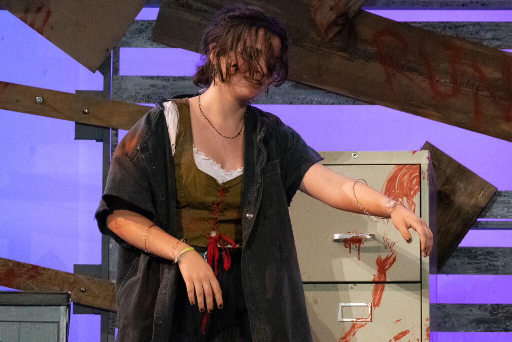 Youth actors performing a dramatic scene onstage at a summer theater camp.
