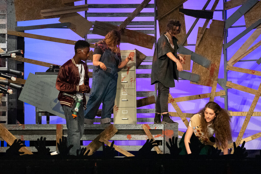 Campers performing a scene onstage with a rotary phone prop during a theater production.