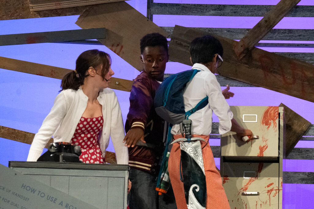 Youth actors performing a dramatic scene onstage at a summer theater camp.