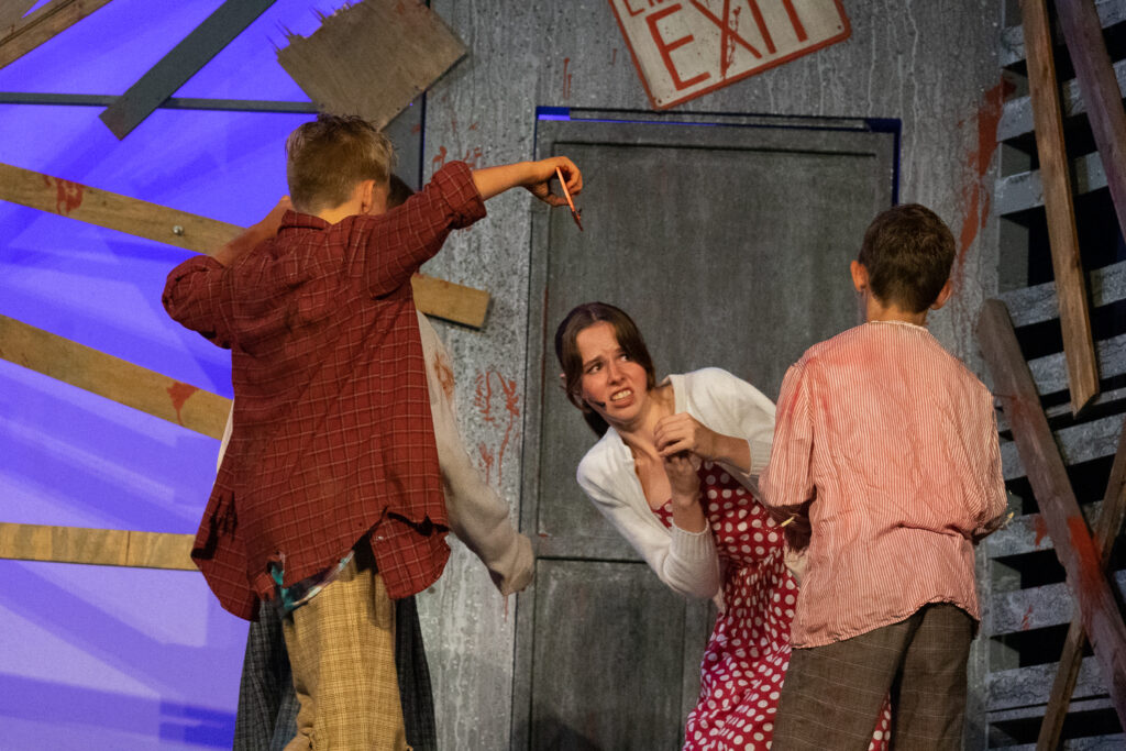 Youth actors performing a dramatic scene onstage at a summer theater camp.