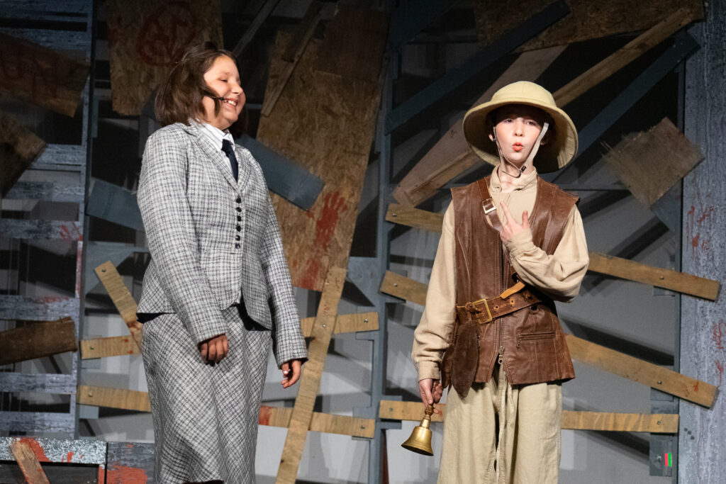 Kids performing a dramatic scene onstage during a theater camp production.