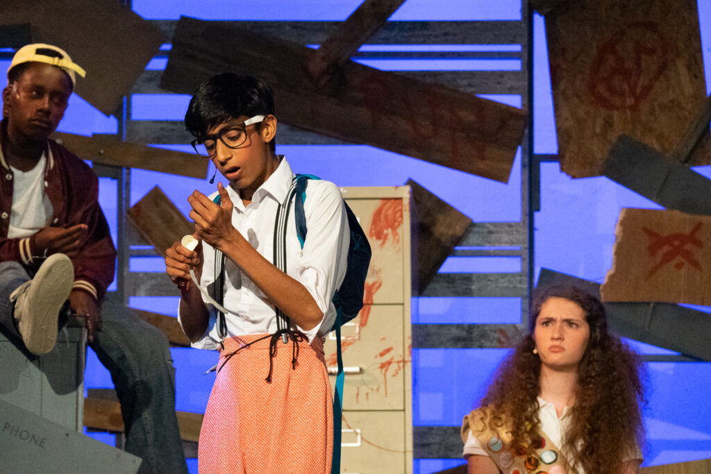 Campers acting in an intense zombie-themed stage production with dramatic set pieces.