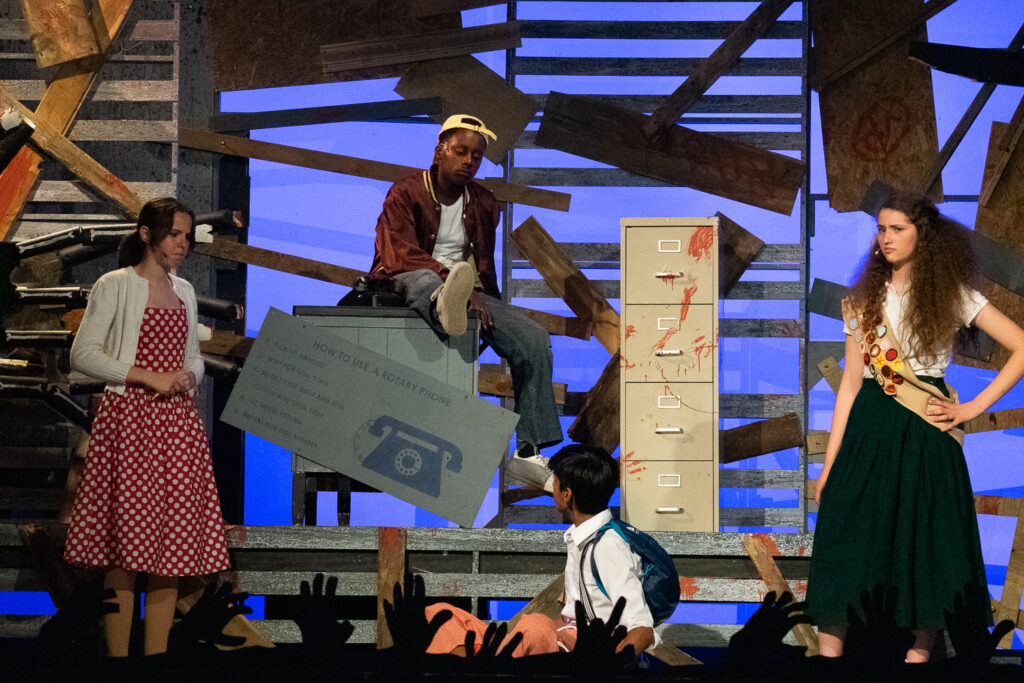 Youth actors performing a dramatic scene onstage at a summer theater camp.