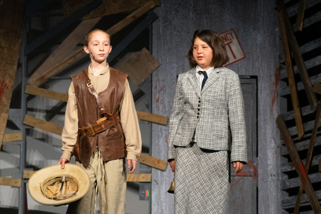 Kids performing a dramatic scene onstage during a theater camp production.