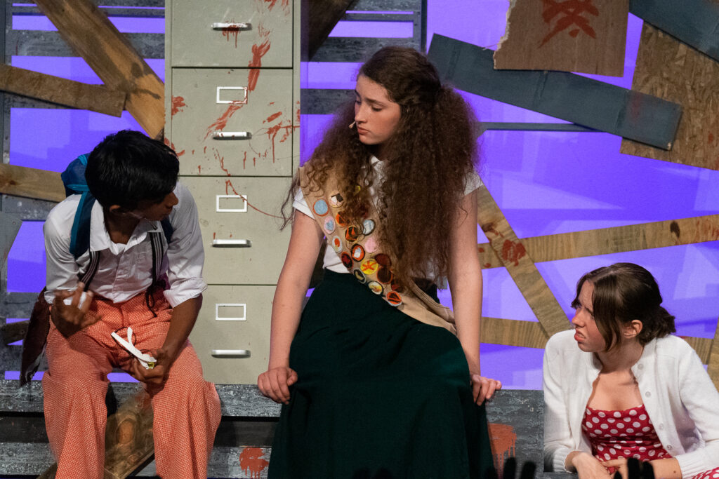 Campers performing a scene onstage with a rotary phone prop during a theater production.