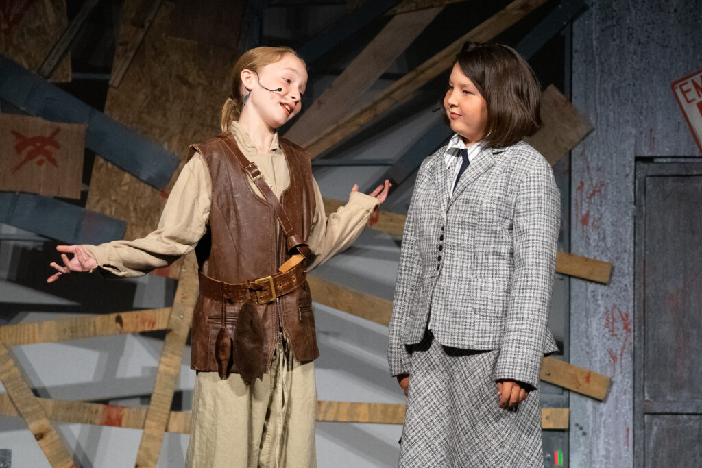 Youth actors performing a dramatic scene onstage at a summer theater camp.