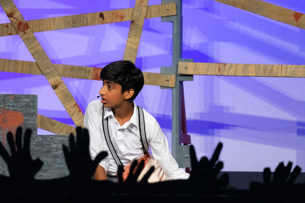 Campers acting in an intense zombie-themed stage production with dramatic set pieces.