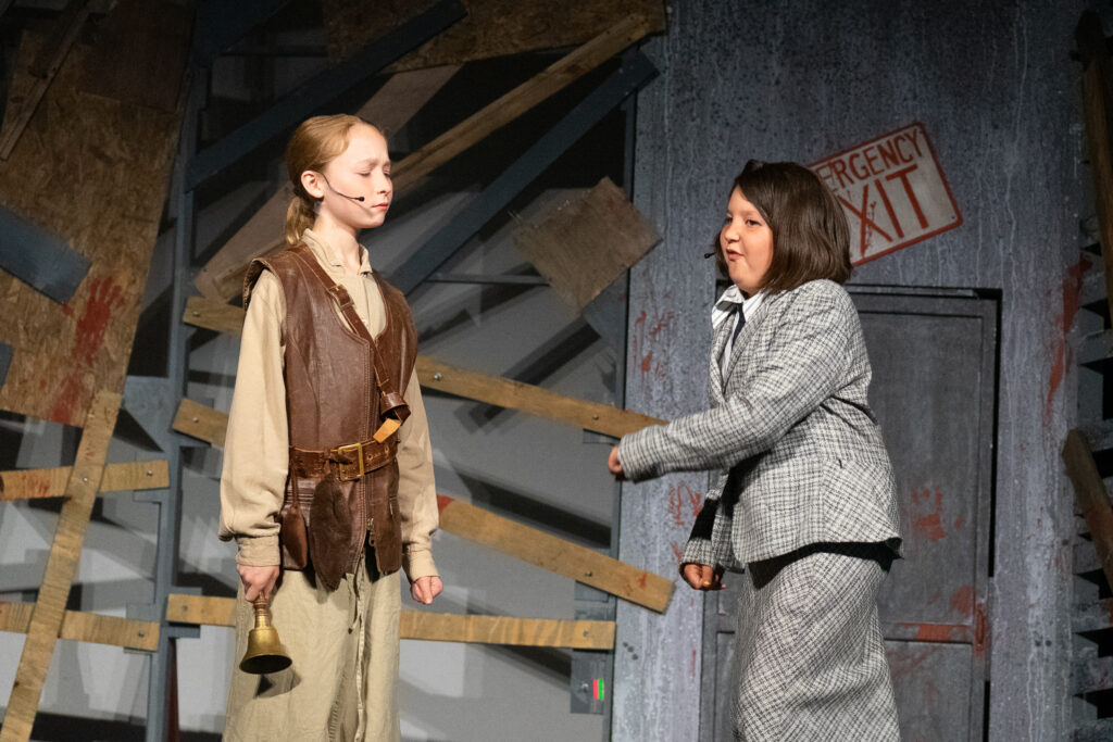 Youth actors performing a dramatic scene onstage at a summer theater camp.