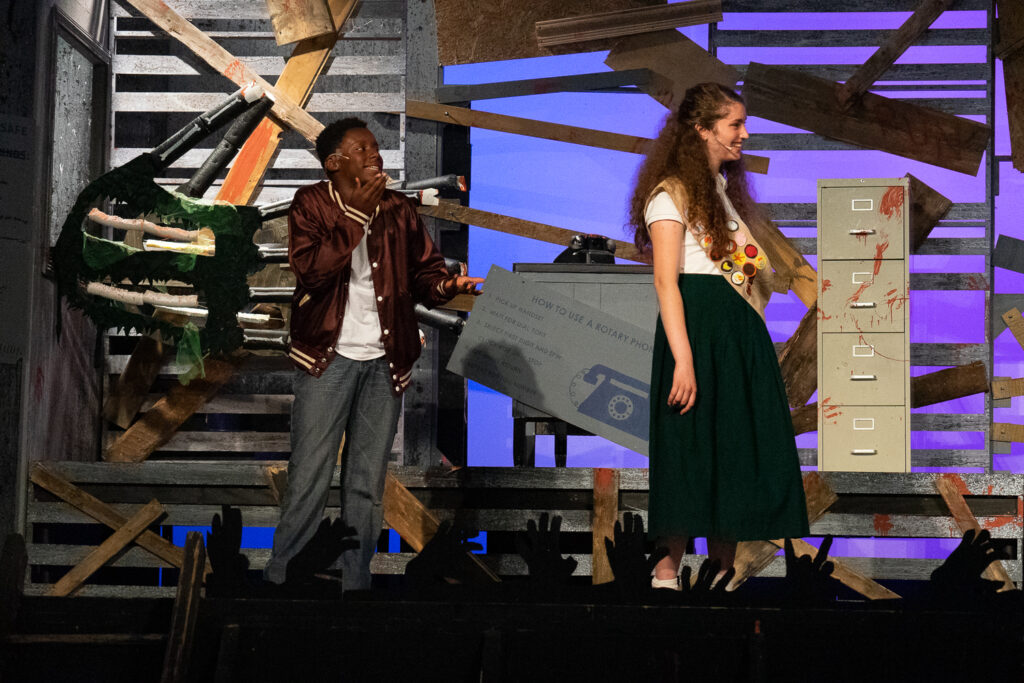 Kids performing a dramatic scene onstage during a theater camp production.