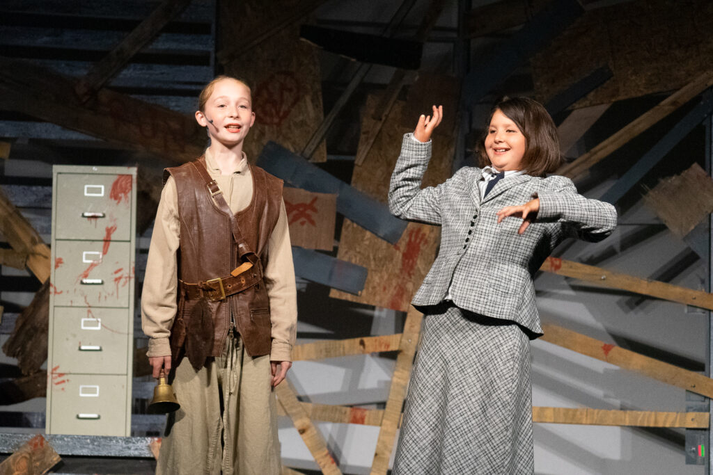Youth actors performing a dramatic scene onstage at a summer theater camp.