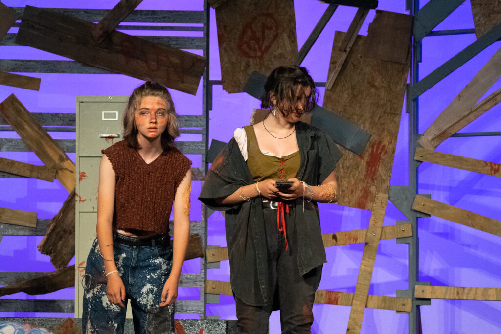 Kids performing a dramatic scene onstage during a theater camp production.