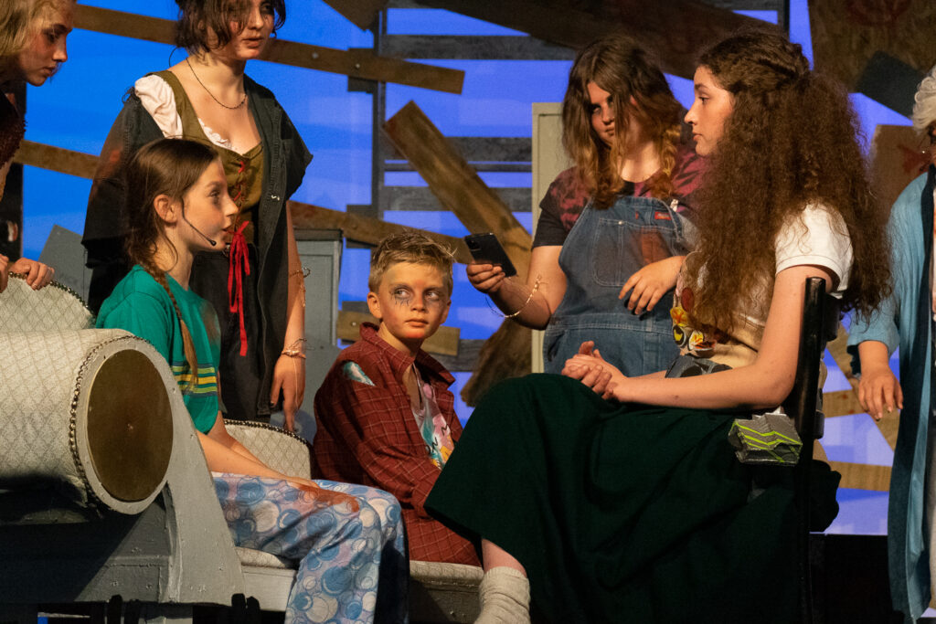 Youth actors performing a dramatic scene onstage at a summer theater camp.