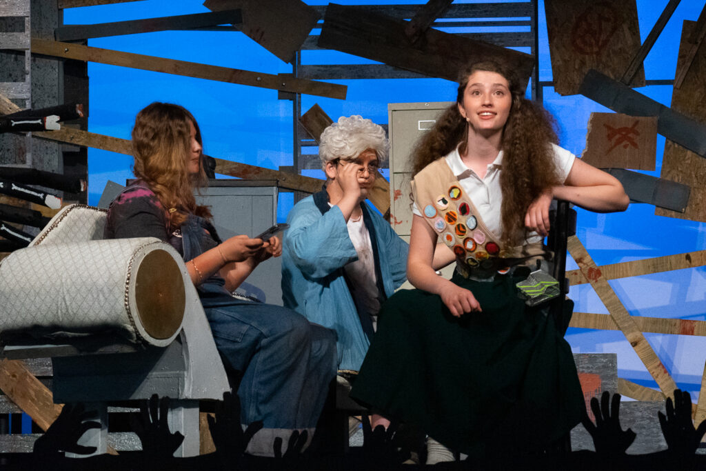 Campers acting in an intense zombie-themed stage production with dramatic set pieces.