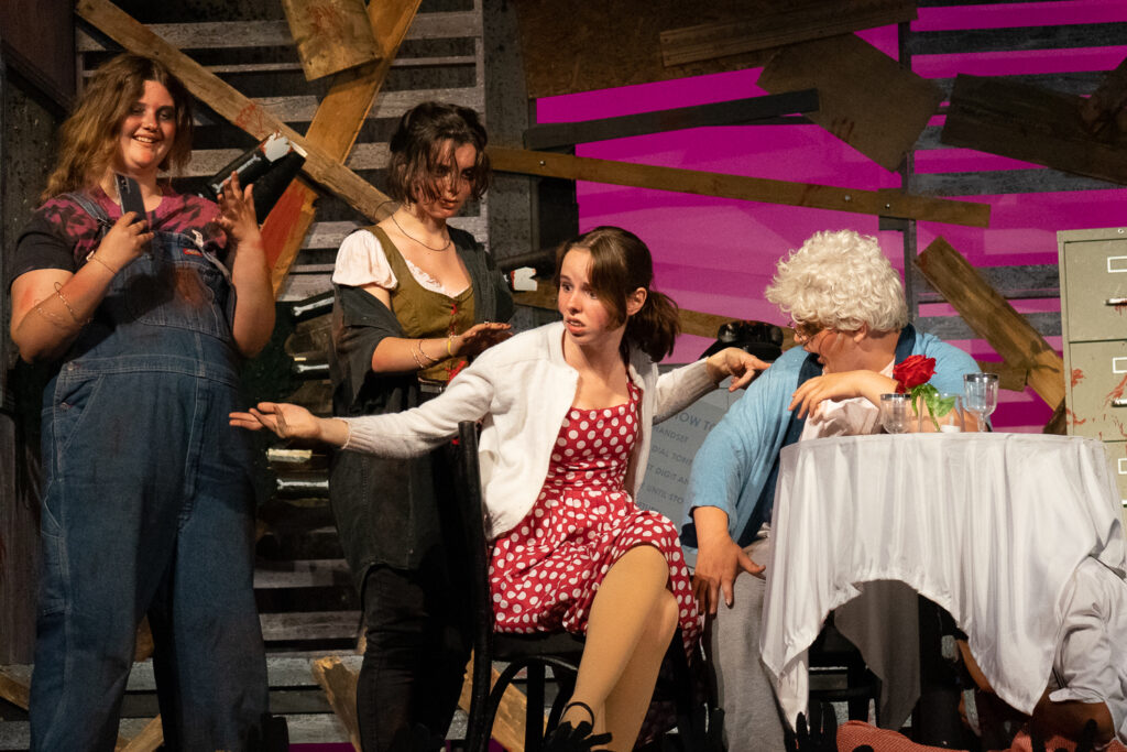 Campers acting in an intense zombie-themed stage production with dramatic set pieces.