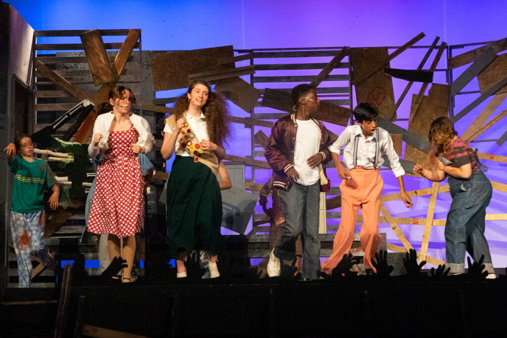 Kids performing a dramatic scene onstage during a theater camp production.