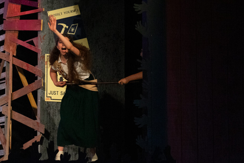 Campers performing a scene onstage with a rotary phone prop during a theater production.