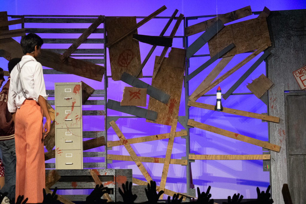 Youth actor performing a dramatic scene onstage at a summer theater camp.