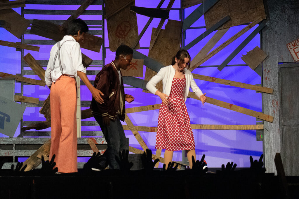 Kids performing a dramatic scene onstage during a theater camp production.