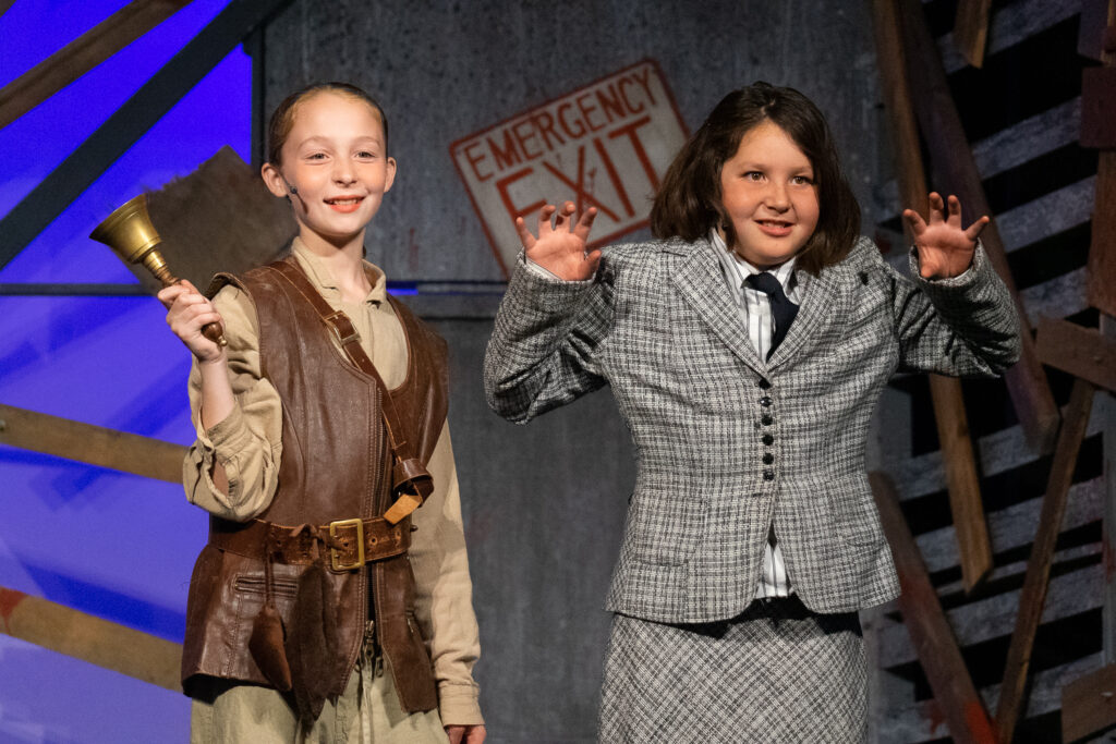 Campers acting in an intense zombie-themed stage production with dramatic set pieces.