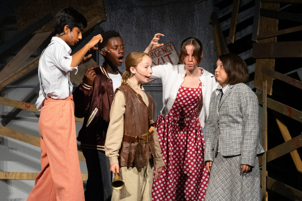 Youth actors performing a dramatic scene onstage at a summer theater camp.