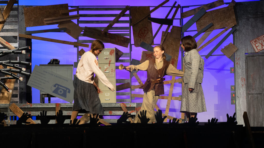 Kids performing a dramatic scene onstage during a theater camp production.