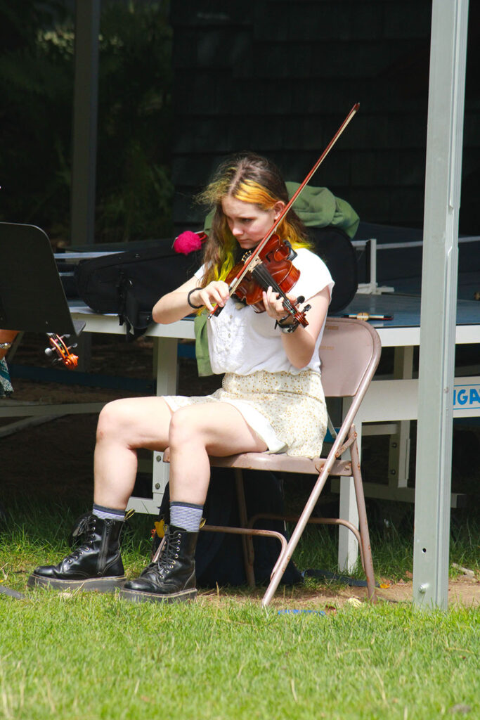 Violinist rehearsing solo outdoors at summer camp