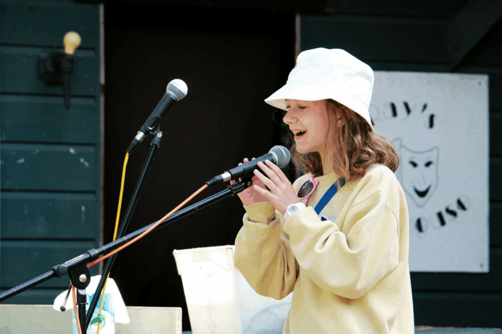 teen-girl-vocal-practice – Long Lake Camp For The Arts Teen girl practicing singing at a performing arts camp with a microphone