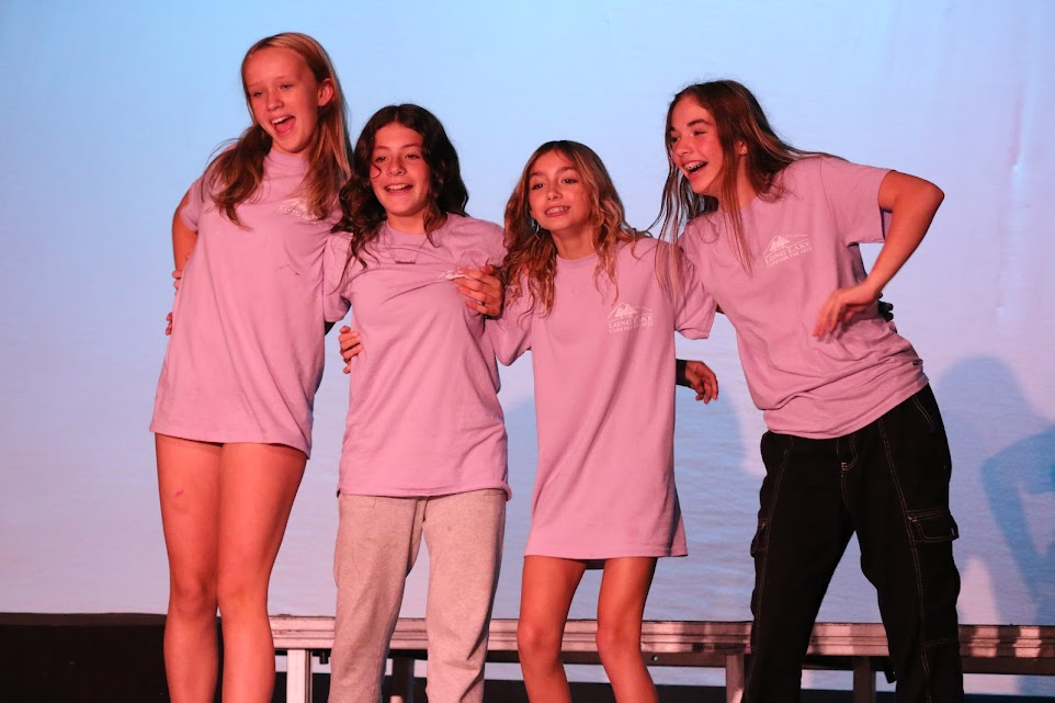 teen-girls-stage-performance-summer-memories – Long Lake Camp For The Arts Teen girls performing on stage at summer camp wearing matching shirts