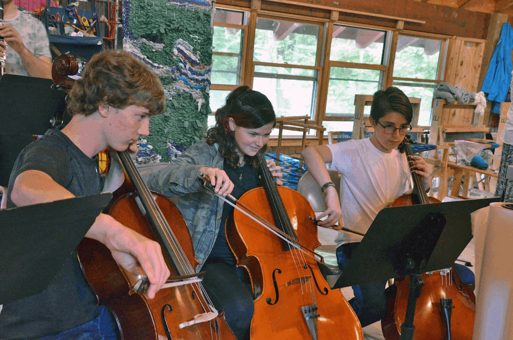 teens-playing-cello-music-class – Long Lake Camp For The Arts A group of teens playing the cello in a music class.