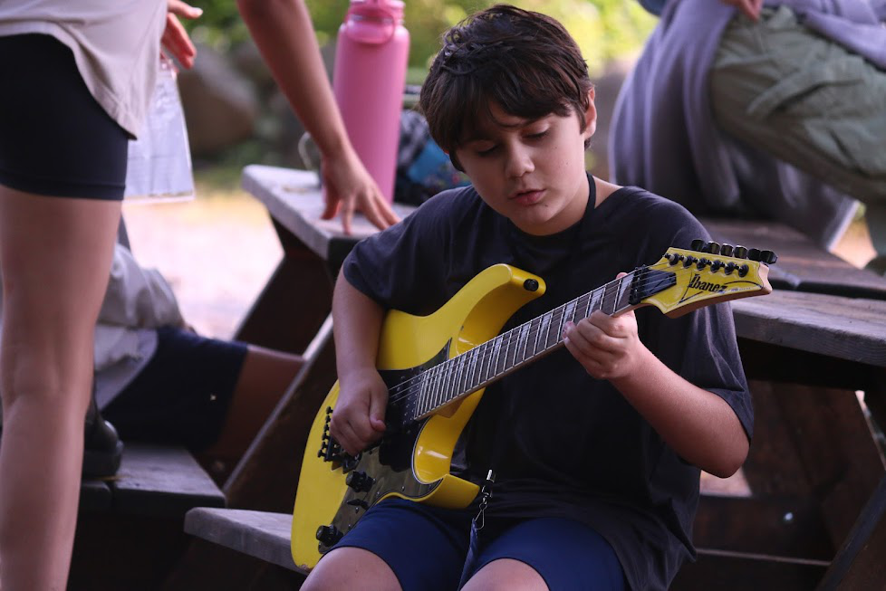 A teenage boy focused on learning guitar from an instructor.