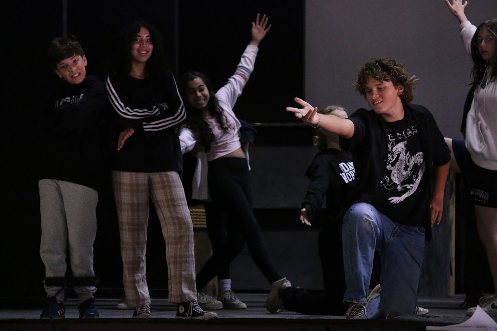 summer-camp-rehearsal-fun – Long Lake Camp For The Arts Kids in casual clothes smiling and striking dramatic poses during a camp theater rehearsal.