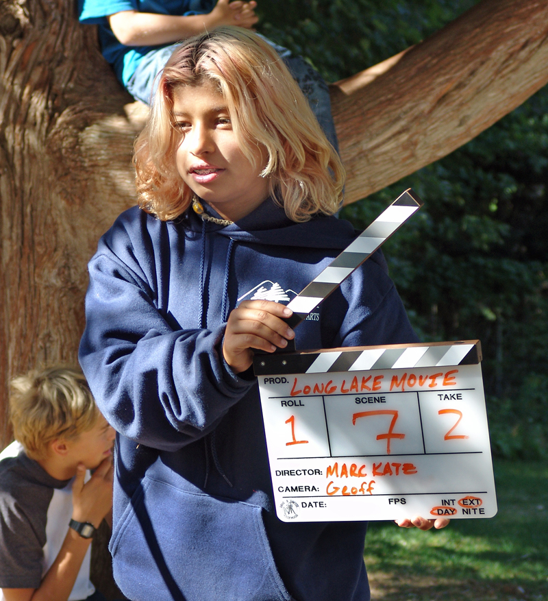 teen-director – Long Lake Camp For The Arts Teen camper acting as a producer, holding a clapperboard during a scene take.