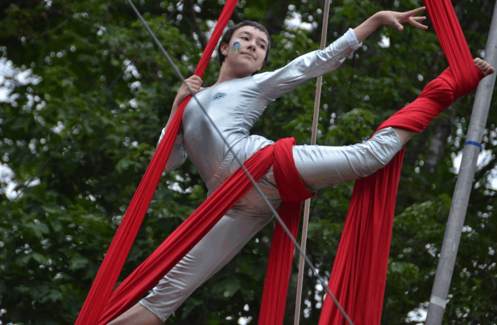 camper-aerial-circus-performance – Long Lake Camp For The Arts A camper executing an aerial trick on a rope during circus set performing original choreography with strength and grace