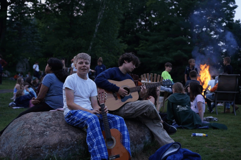 teen-boys-guitar-campfire-jam-night-performing-arts-camp – Long Lake Camp For The Arts Teen boys sitting around a campfire, jamming and laughing with their guitars
