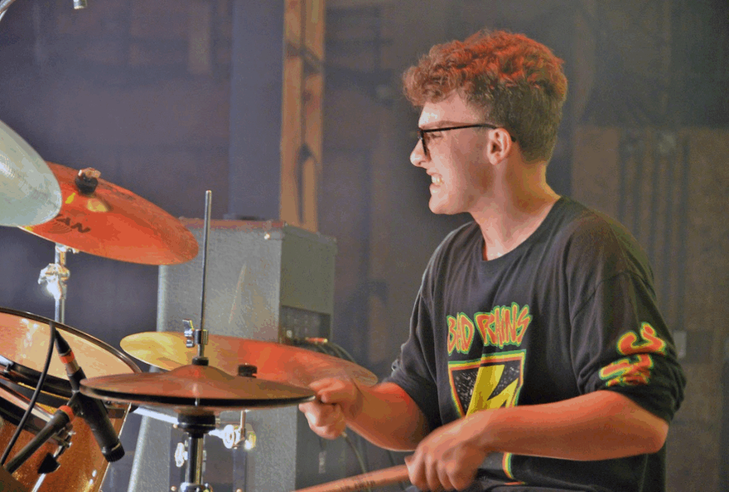 teen-drummer-rock-camp-2025 – Long Lake Camp For The Arts A teen camper playing drums passionately on stage with confidence and energy at a rock camp performance
