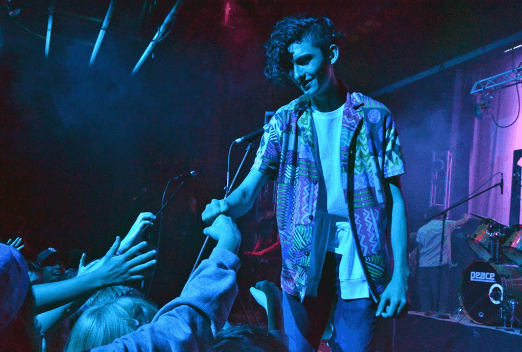 teen-rock-performance-visual-arts-summer-camp – Long Lake Camp For The Arts A teen camper fist-bumping the crowd after a high-energy rock performance at a rock night