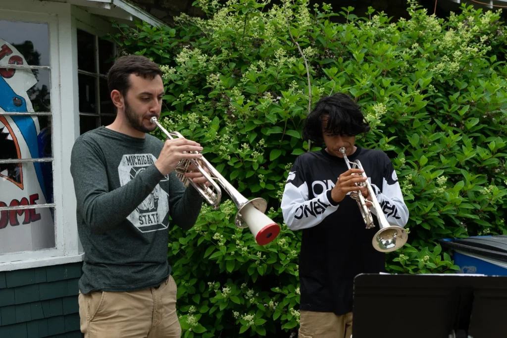 Music teacher instructing a camper as they practice the trumpet together at music camp