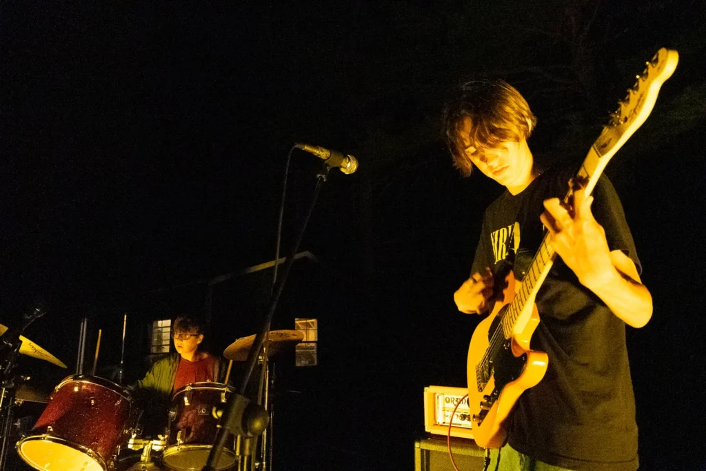 00117_Hayden_RockNight3_0570 – Long Lake Camp For The Arts Camper playing guitar on stage during rock night at a sleepaway performing arts camp.