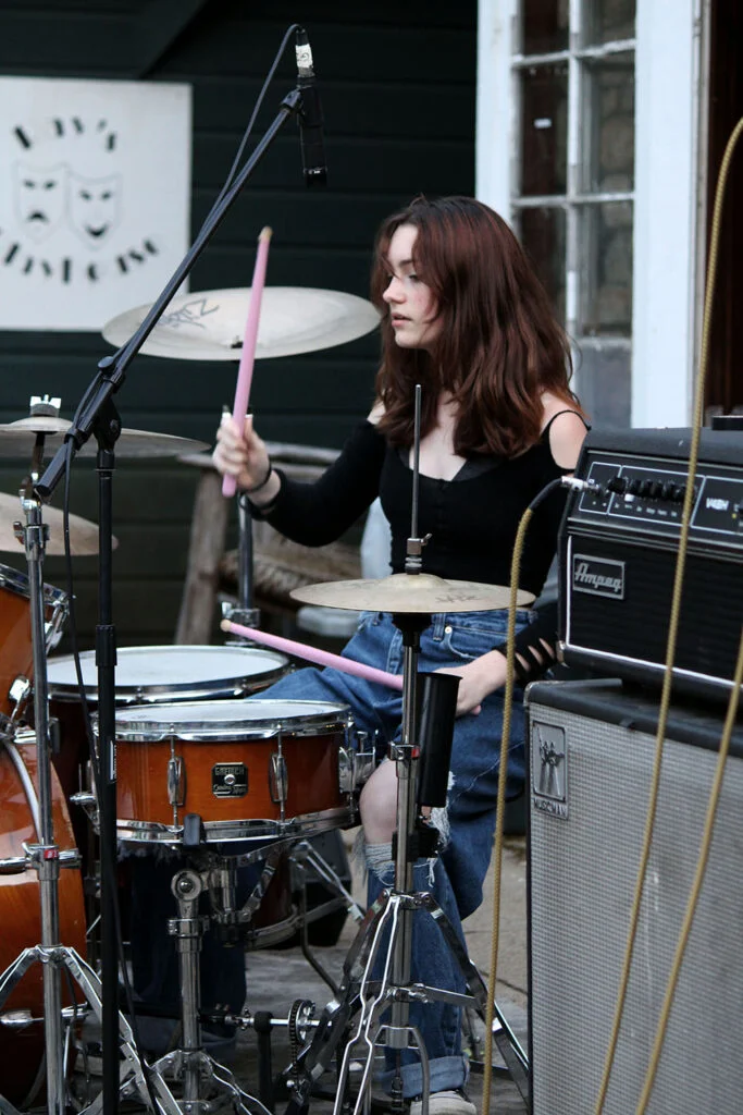 2-3-683x1024 – Long Lake Camp For The Arts Teen camper confidently playing drums during a music session.