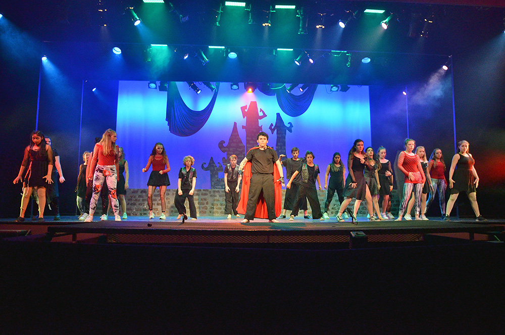 full-cast-performance-stage-lights – Long Lake Camp For The Arts Full cast performing under stage lights at a summer performing arts camp