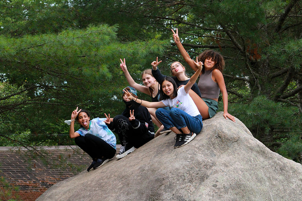 Teen campers posing together on a rock
