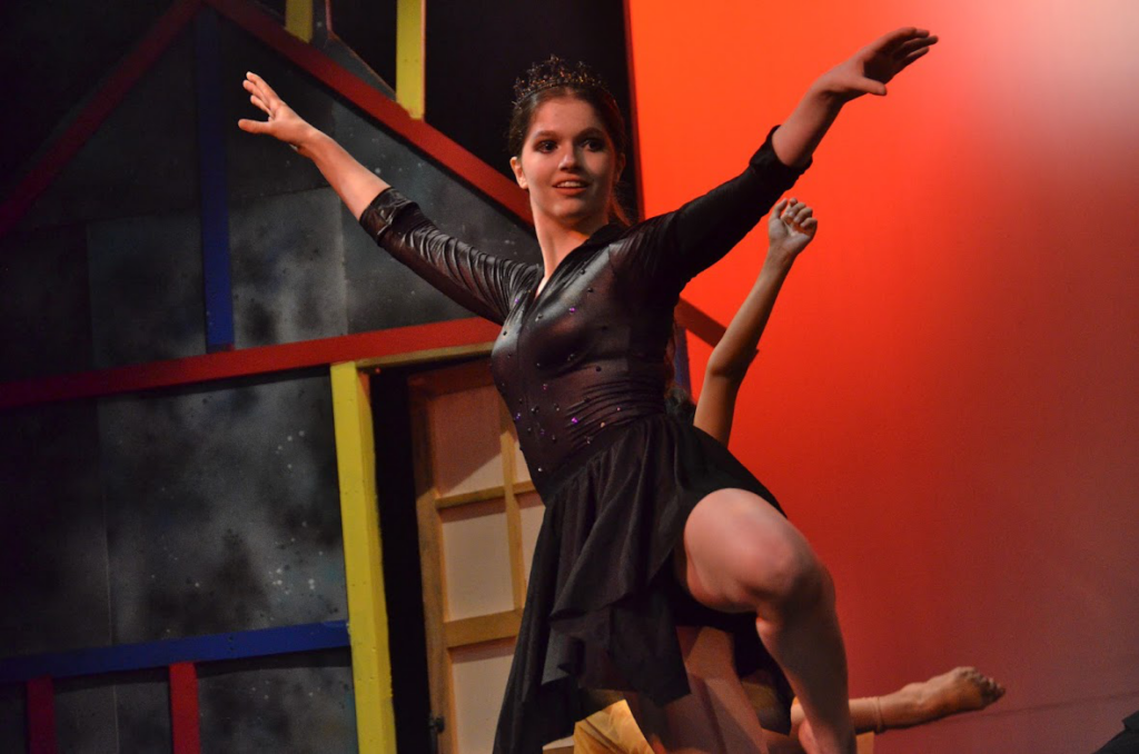 Picture20 – Long Lake Camp For The Arts Camper dancing on stage in costume with dramatic lighting and smoke effects